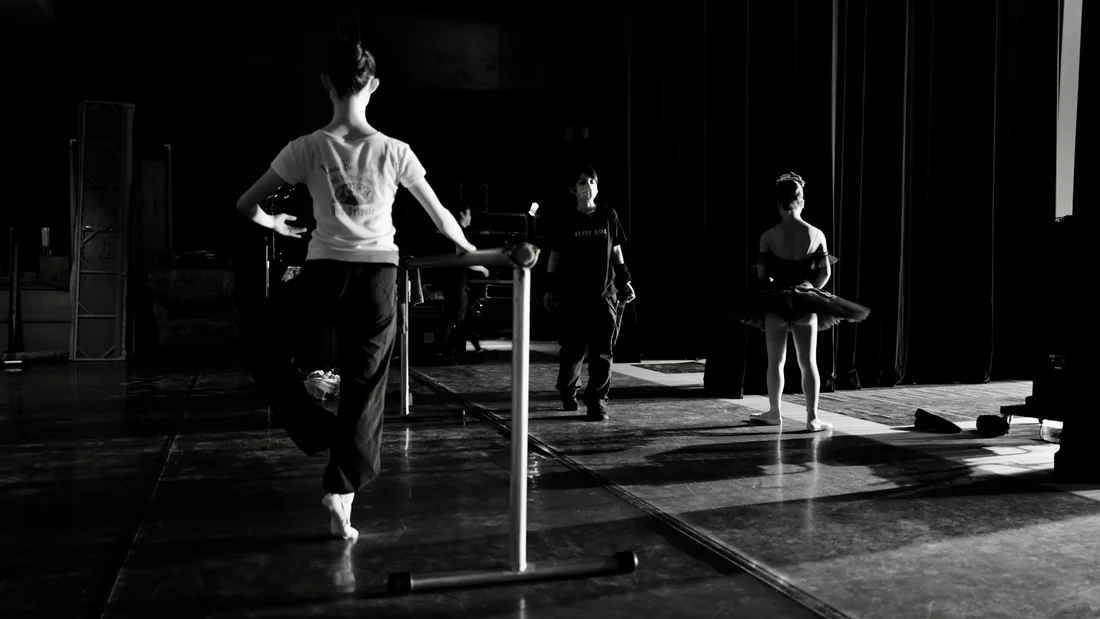 Bailarinas ensayando junto a una barra portátil en una sala de trabajo con luz lateral